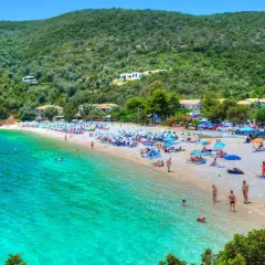 Piękna plaża z turkusową wodą, zielone wzgórza i domki w tle. To idealne miejsce na wakacje na Karaibach, wyspy zapraszają do odpoczynku.