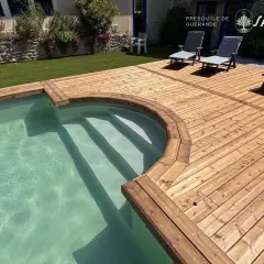 Terrasse en bois classe 3 ou 4, bordant une piscine aux eaux claires. Des chaises longues invitent à la détente sur ce bois chaleureux.