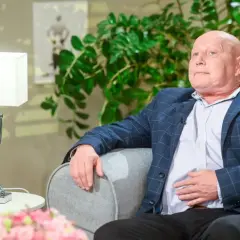 Krzysztof Jackowski w okryciu w kratę, oparty o sofę, jakby snuł najnowsze przepowiednie.