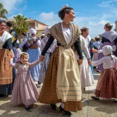 Un groupe danse en cercle, portant une tenue traditionnelle française homme et femme, avec des coiffes et des jupes colorées.