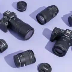 A collection of Canon EOS R cameras and various best L series lenses, including zooms and primes, are artfully arranged on a lavender background.
