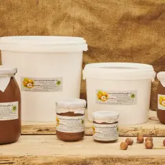 Vasi e secchielli di deliziosa pasta di nocciole, con nocciole fresche in primo piano.