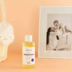 Aceite hidratante de almendras, ideal para el cuidado de la piel durante el embarazo. Cesta de mimbre y foto familiar al fondo.