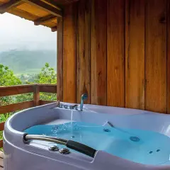 A newly completed hot tub installation on a wooden deck, overlooking a misty mountain landscape.