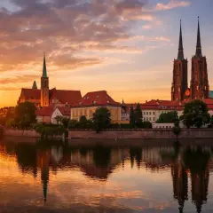 Zachód słońca nad Odrą we Wrocławiu, województwo. Katedra i zabytkowe budynki odbijają się w wodzie.