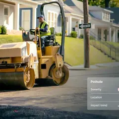 A worker operates a steamroller, ready to be a change agent and fix the high-severity pothole on this street.