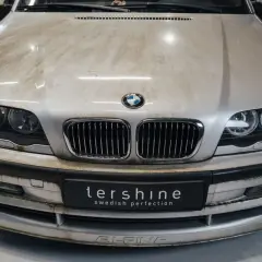 En smutsig silverfärgad BMW med synliga fläckar på huven och stötfångaren. Dags att avfetta bilen för att få fram dess glans.