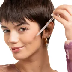 Una donna applica un siero viso con contagocce. Scopri a cosa serve la vitamina C per il viso per una pelle luminosa.