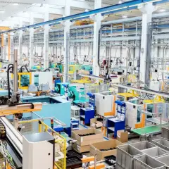 Nowoczesna hala produkcyjna z liniami maszyn, robotami i taśmociągami. Efektywne zarządzanie produkcją w akcji.