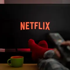 Relaks przy **Netflix w Play**. Czerwone skarpety, kubek i pilot w dłoni zapraszają do seansu.