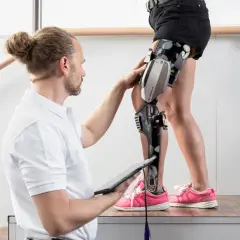 Therapeut passt c-brace an. Voraussetzungen für die Nutzung werden geprüft, während die Person auf einer Holzplattform steht.