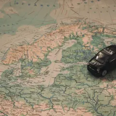 Czarny samochodzik na mapie Europy, planujący trasę jak dojechać do Mikołajek.