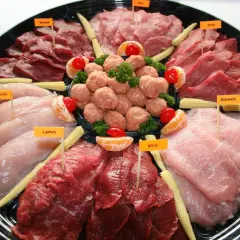 Plateau de viandes variées pour fondue : poulet, agneau, bœuf, porc, veau et gibier, décoré de mini-maïs et d'agrumes.