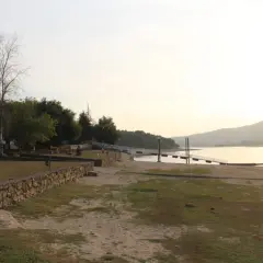 Un tranquilo atardecer en la playa fluvial o corgo, con un muelle y vegetación verde.
