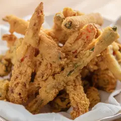 Crispy, golden-brown vegetable sticks coated in a light, airy gluten free tempura batter, served in a white bowl lined with a napkin.