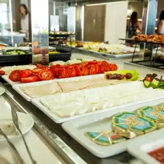Una variada selección de quesos, fiambres y tomates frescos en una barra de buffet, como en una taberna oasis.