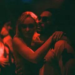 Jocelyn und Tedros in einer innigen Umarmung, beleuchtet von rotem Licht. Ein Moment aus "The Idol Serie", der die Intensität der Beziehung einfängt.