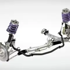 Sistema de suspensión automotriz con amortiguadores morados, frenos de disco y una barra estabilizadora negra que conecta ambos lados.