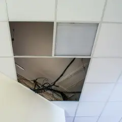 Schema distanza montanti controsoffitto cartongesso: cavi elettrici a vista in un'apertura del controsoffitto modulare.