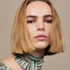 Modelka z idealnie prostymi, rudymi włosami w stylu blunt bob, z delikatnym makijażem oczu i ust, prezentuje się elegancko.