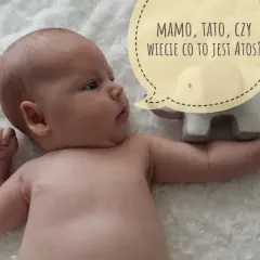 Niemowlę w pozycji szermierza, z pluszowym słoniem i dymkiem: "Mamo, tato, czy wiecie co to jest Atos?".