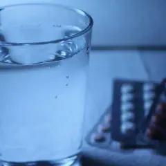 Szklanka wody obok opakowań leków. Czy to melatonina i alkohol, czy tylko złudzenie?
