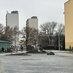 Prace brukarskie w Serbinowie. W tle bloki mieszkalne i zielona budka.
