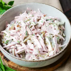 Schmackhaftes Fleischsalat-Rezept in einer Schüssel, garniert mit Schnittlauch und Gewürzgurken. Perfekt für ein schnelles Mittagessen.