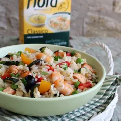Un'appetitosa insalata di riso con pesce, gamberi, verdure e olive nere, pronta per essere gustata.