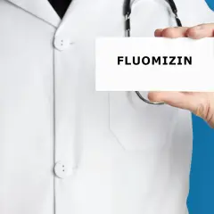 Lekarz w białym kitlu trzyma kartkę z napisem FLUOMIZIN. Stetoskop wisi na jego szyi.