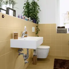Bagno moderno con piastrelle color sabbia, lavabo sospeso, WC e vasca. Un'idea per dipingere piastrelle bagno con un tocco di calore.