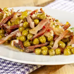 Un piatto invitante di piselli e pancetta croccante, guarnito con foglie di salvia fresca. Un classico sapore italiano.