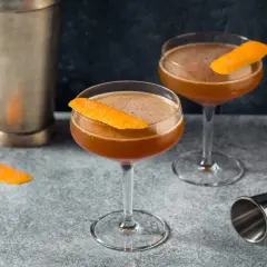 Zwei elegante Cocktails, garniert mit Orangenschale, stehen bereit. Ein "Blood and Sand Cocktail" wartet auf seinen Genuss.