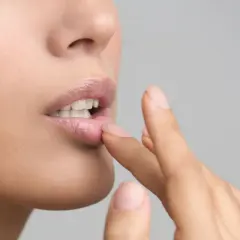 Une femme applique un baume sur ses lèvres. Si vous avez des lèvres gercées, que faire ? Hydratez-les !