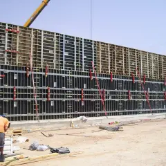 Un ouvrier travaille sur un grand petit coffrage béton, prêt pour le coulage. La structure métallique est impressionnante.