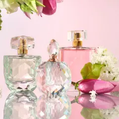 Eleganckie flakony perfum i wody toaletowej, otoczone kwiatami. Różnica między nimi tkwi w stężeniu olejków zapachowych.