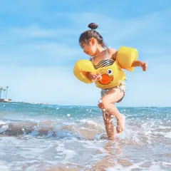 Radosna dziewczynka w żółtym kaczuszce bawi się na plaży. Idealna turcja pogoda maj na wakacje.