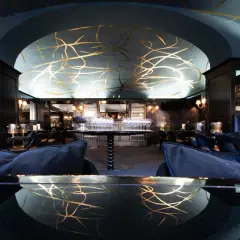 Interni eleganti di uno dei **best bars in Turin**, con soffitto blu decorato d'oro e divanetti in velluto.