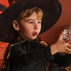 Niño mago con sombrero y capa, sosteniendo una botella con forma de calavera. ¡Perfecto para trucos de magia para niños de 3 a 6 años!