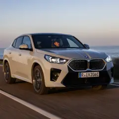Beżowe BMW iX2 jedzie wzdłuż wybrzeża.