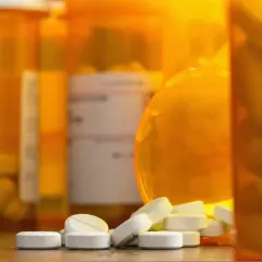 Białe tabletki rozsypane przed pomarańczowymi buteleczkami. Czy to oxycodone, co to za lek?