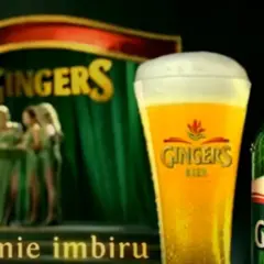 Piwo Gingers: orzeźwiający smak imbiru w szklance i butelce, na scenie z tancerkami.