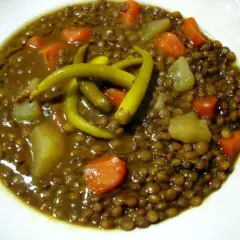 Un plato de lentejas con verduras, patatas y guindillas verdes. Un guiso reconfortante y nutritivo.