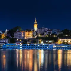 Nocny widok na Belgrad, stolicę Serbii, z rzeką i statkiem wycieczkowym.
