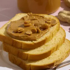 Stos kanapek z masłem orzechowym, z orzeszkami na wierzchu. Czy pies może masło orzechowe? To pytanie nurtuje wielu właścicieli czworonogów.