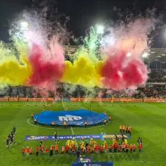 Oprawa meczu Korona Kielce – Jagiellonia Białystok. Piłkarze wychodzą na murawę w otoczeniu gęstego dymu w barwach żółto-czerwonych.