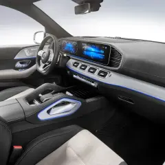 Interior de un Mercedes moderno, con pantallas digitales, asientos de cuero y detalles de iluminación ambiental azul.