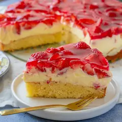 Ein saftiger Erdbeer Schmand Kuchen Springform, mit frischen Erdbeeren und rotem Tortenguss, auf einem Teller mit einer Gabel.