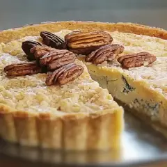 Une part de quiche au bleu, garnie de noix de pécan, sur une assiette.