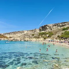 Słoneczny dzień w Paradise Bay na Malcie. Turkusowa woda, piaszczysta plaża i skaliste klify tworzą idylliczny krajobraz.